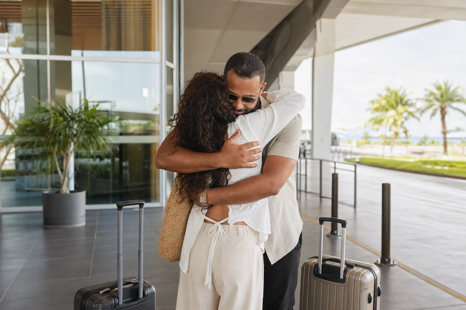 Une femme souriante et un homme riant se tiennent la main, symbolisant la joie des retrouvailles et le soutien mutuel dans une relation à distance.